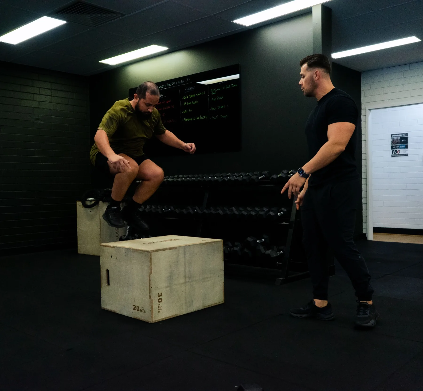 Client landing a box jump in a coached gym session