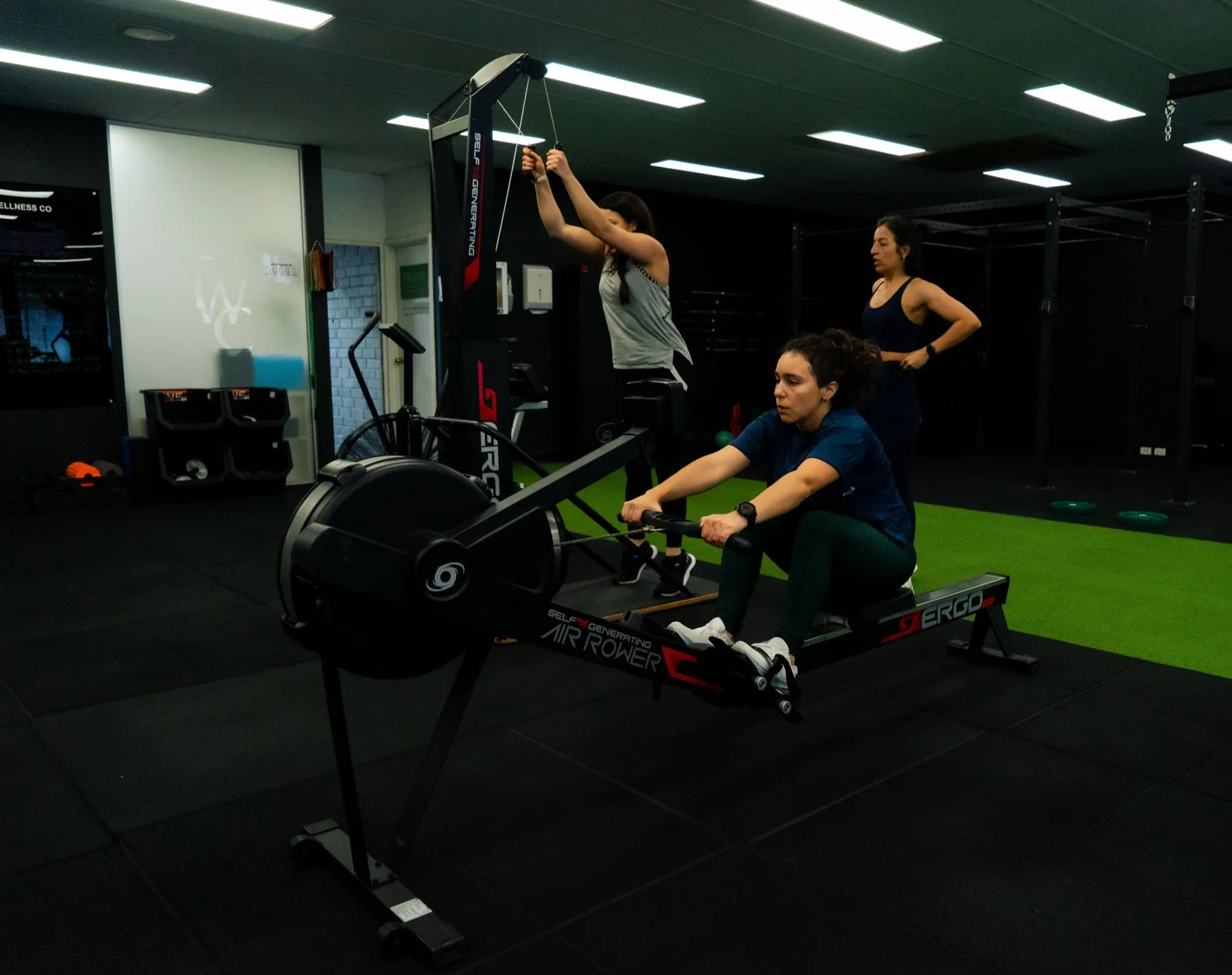 Client using the ski erg while others row behind her