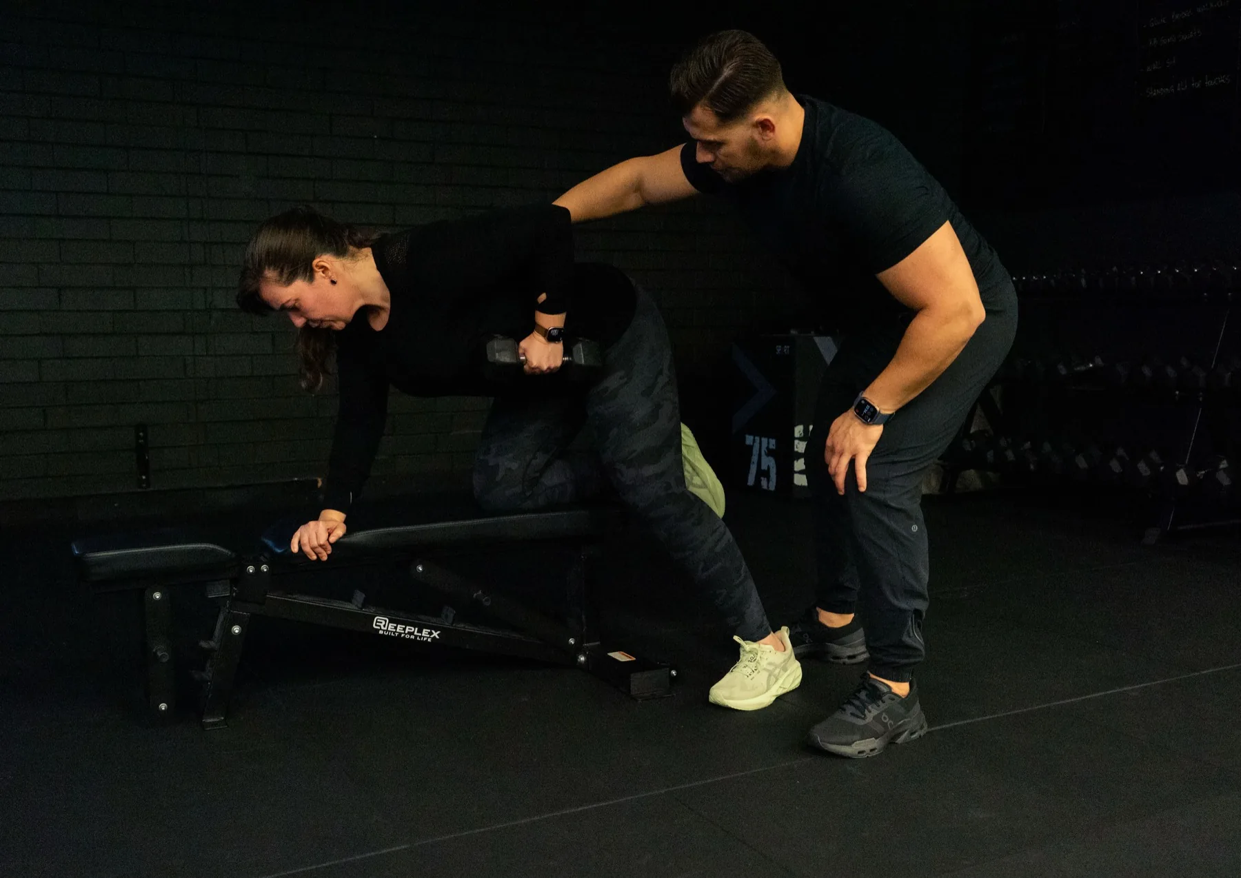 Hudson coaching a client through supported dumbbell rows