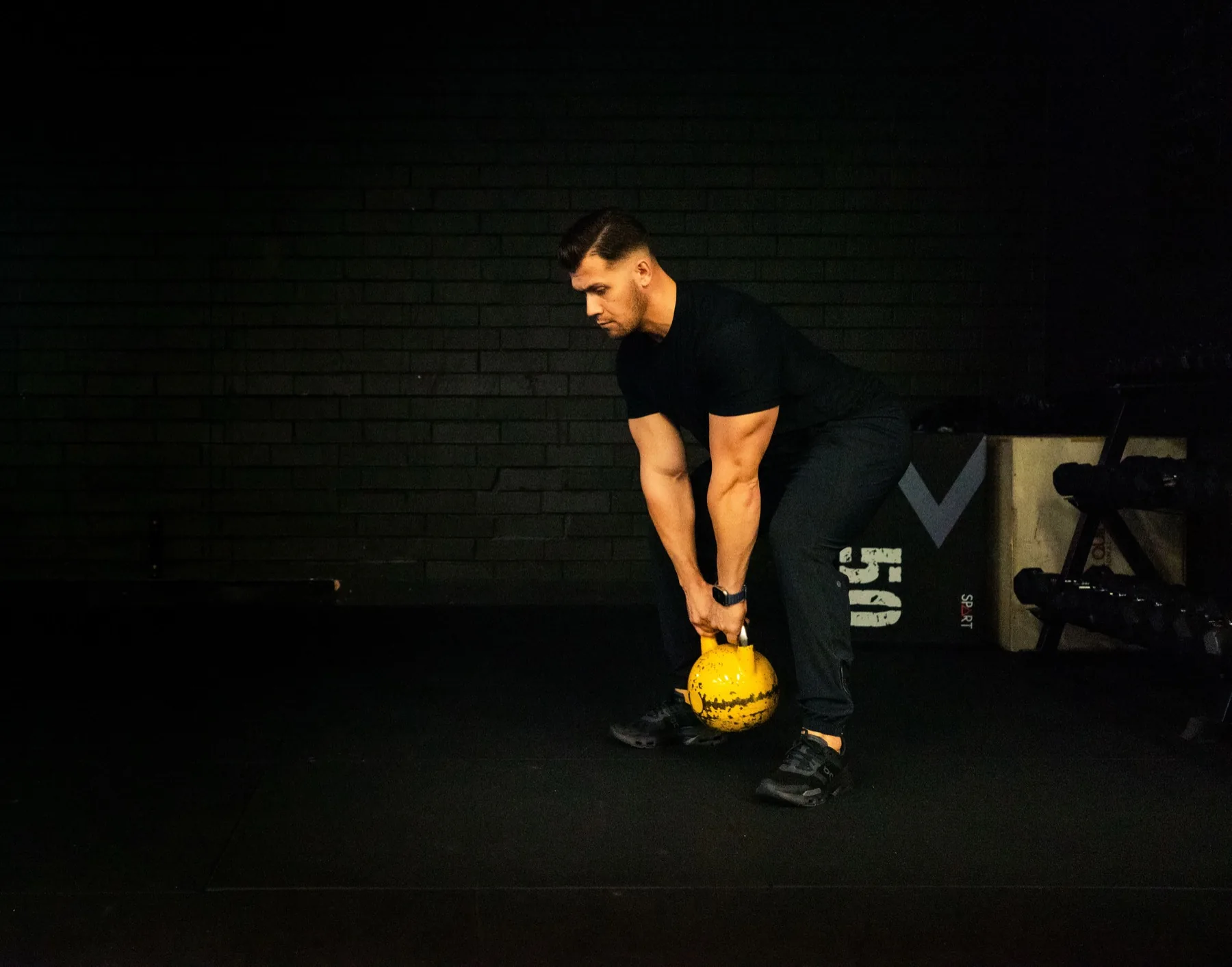 Hudson practicing a kettlebell hinge with a yellow kettlebell