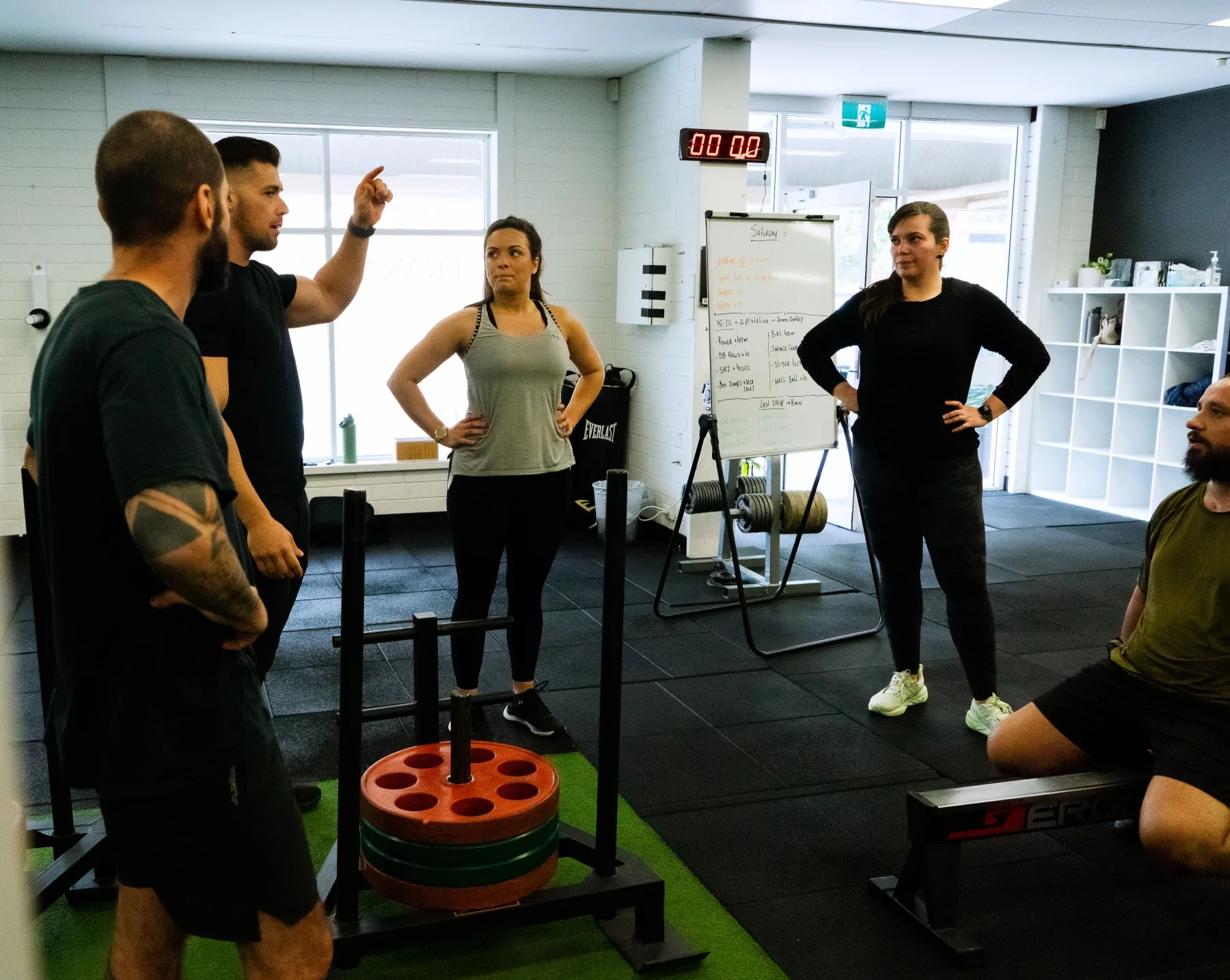 Hudson explaining the workout beside the sled station