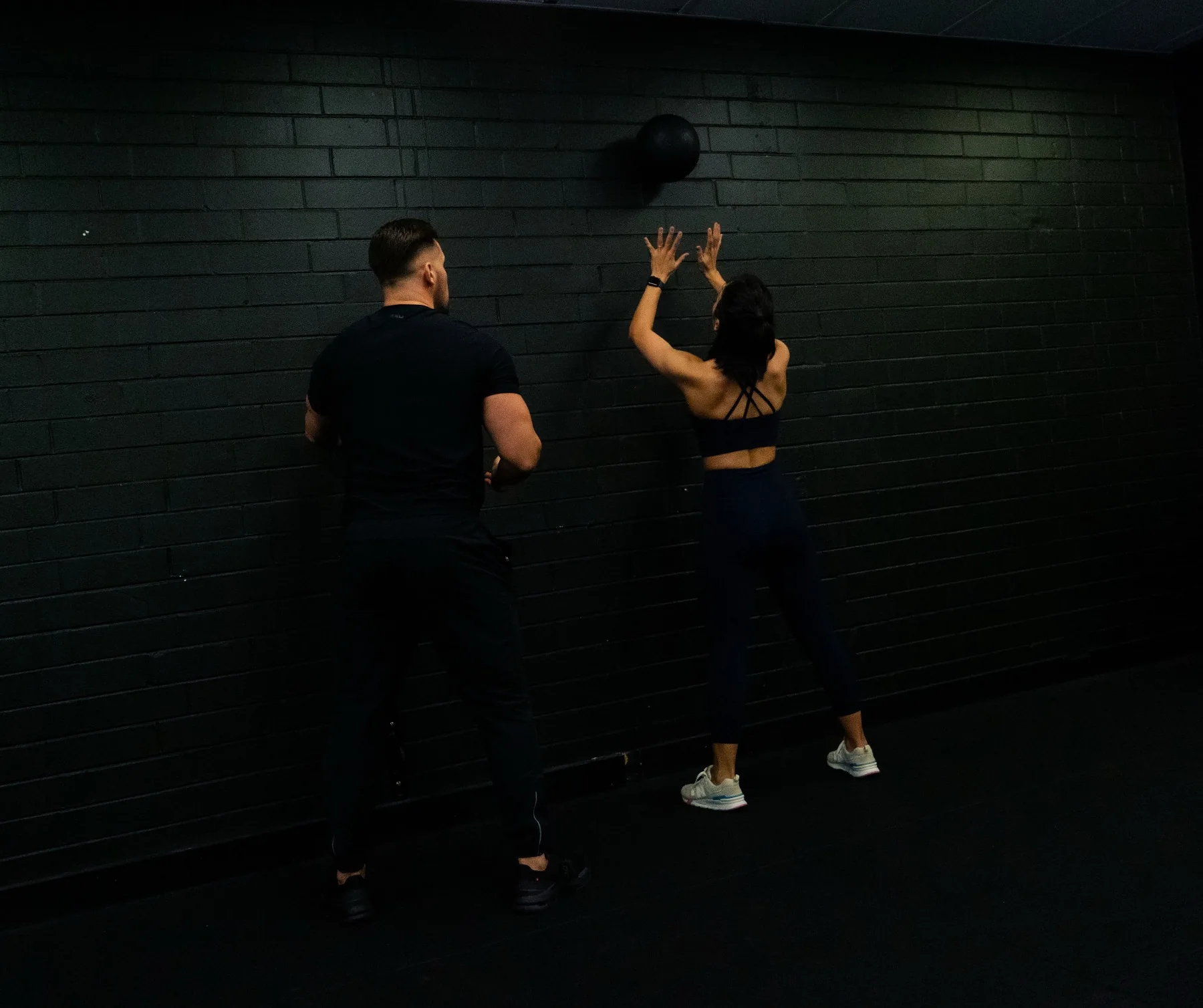Client finishing a wall ball rep while Hudson observes