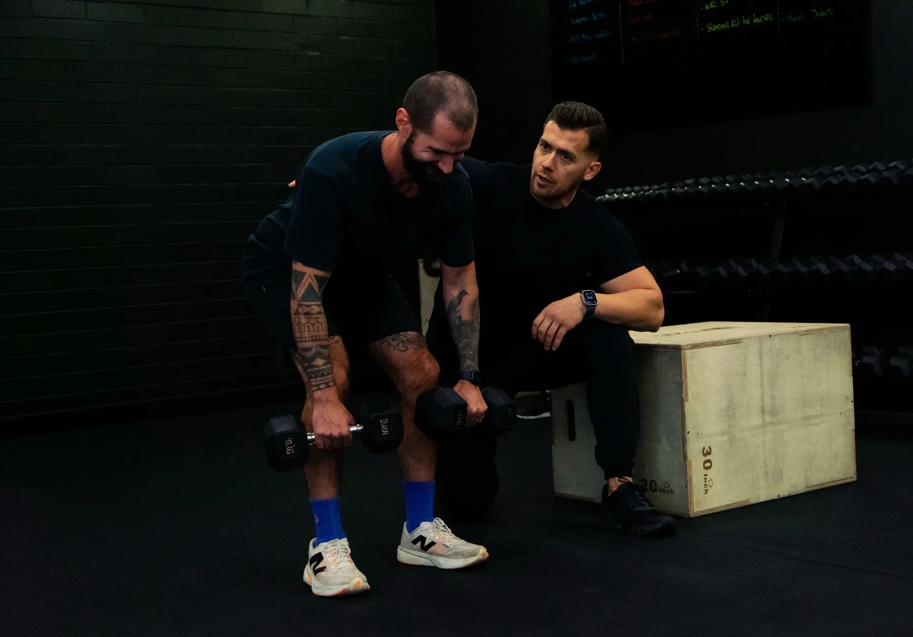 Client training dumbbell rows with Hudson coaching close by