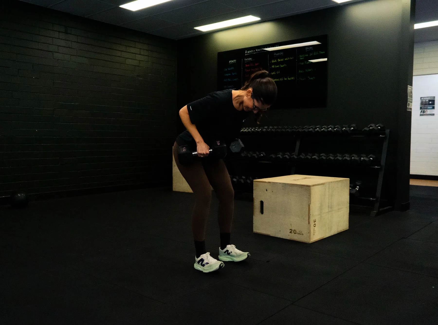 Client training upper body with dumbbells near a plyo box