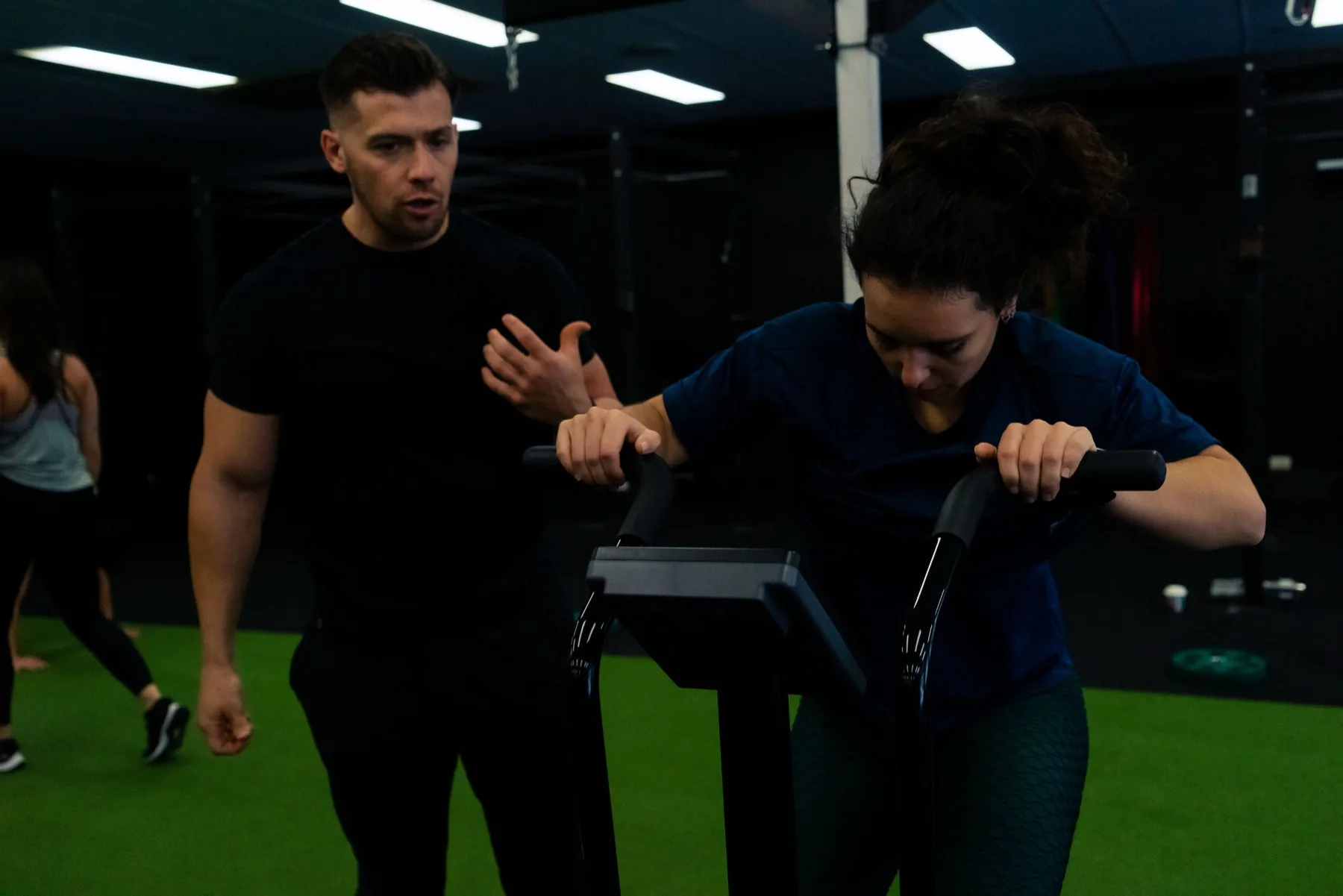 Client rowing while a coach monitors technique