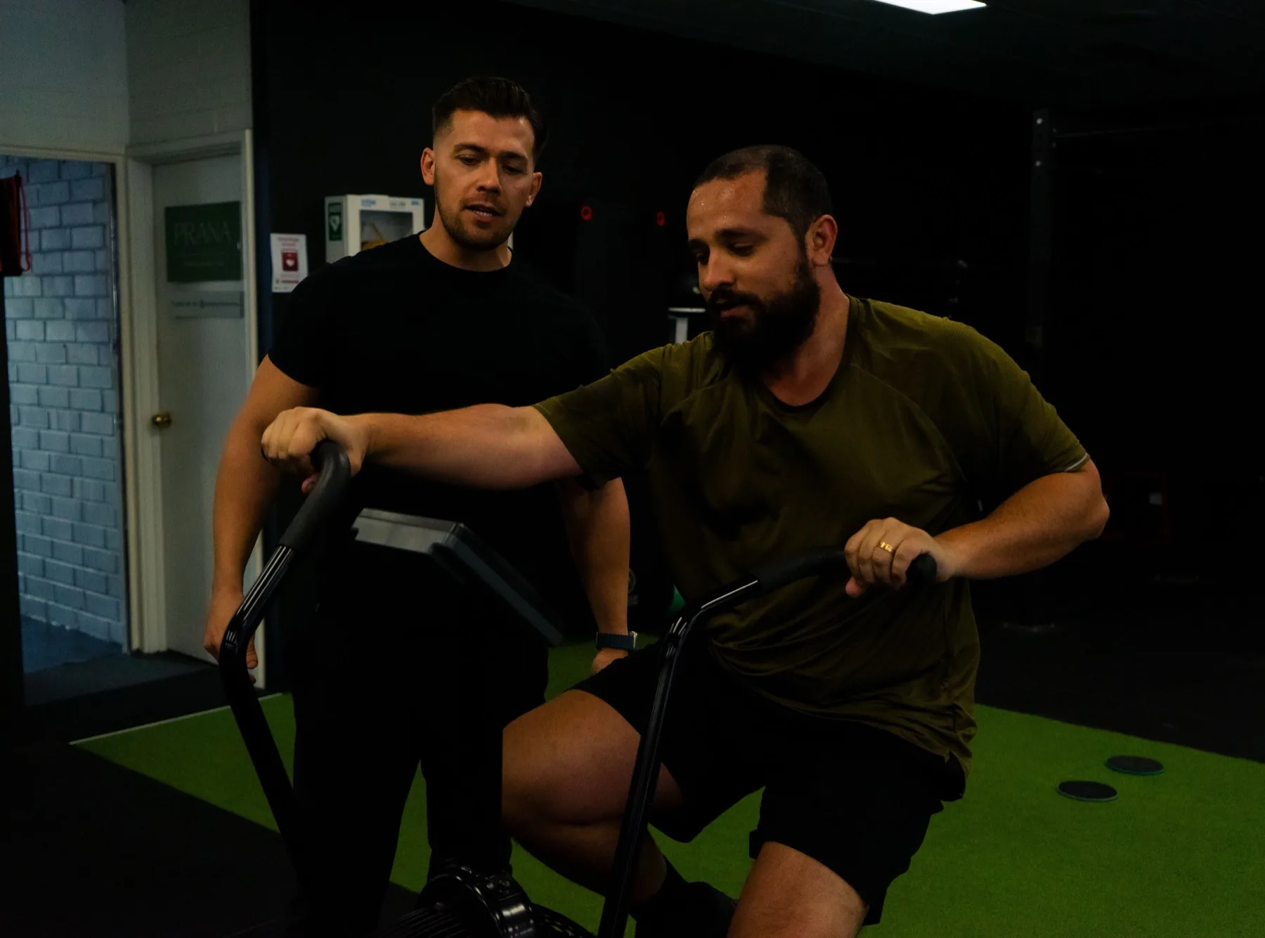 Coach assisting a client on the air bike during cardio work