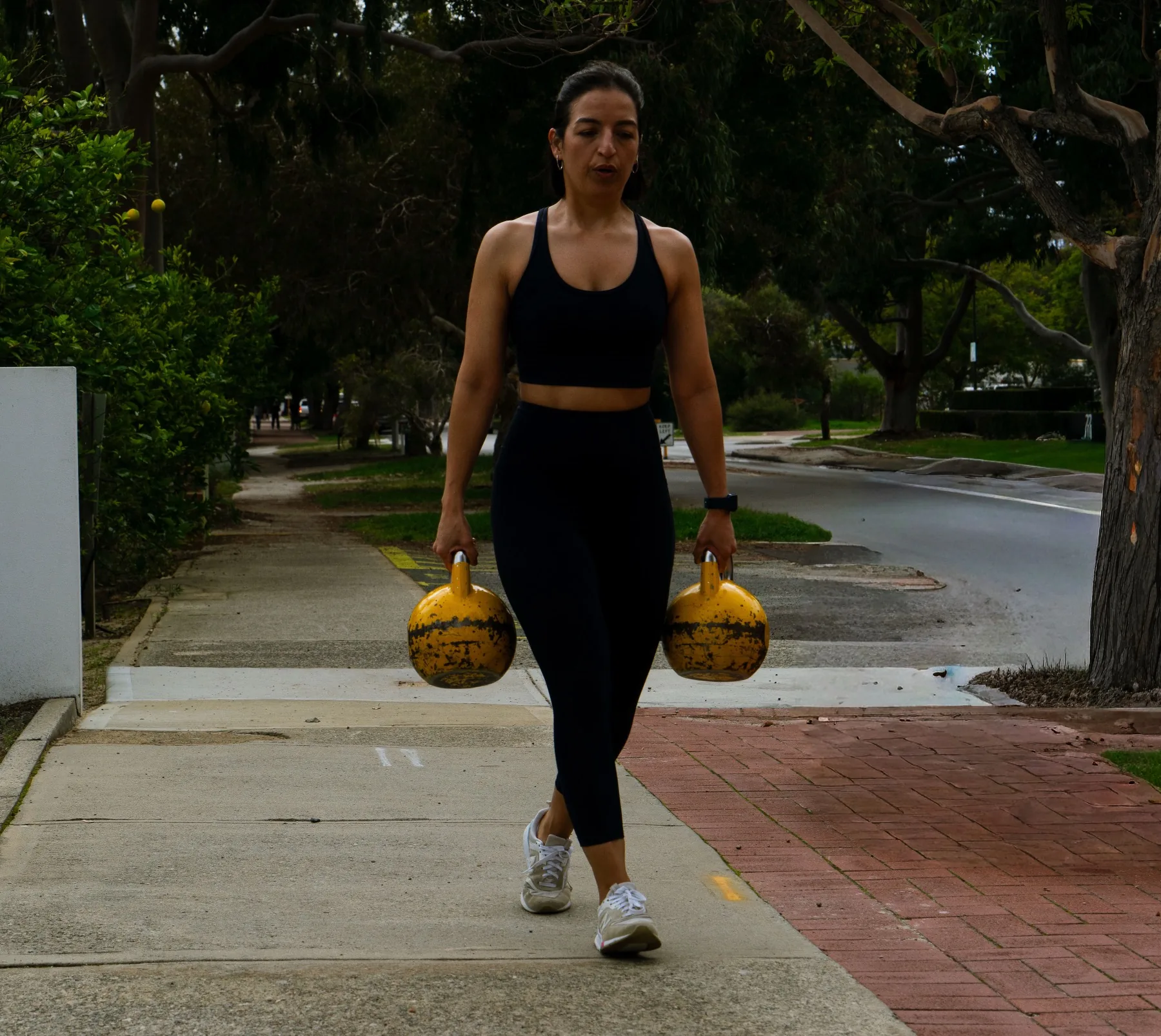 Client carrying kettlebells outdoors during training