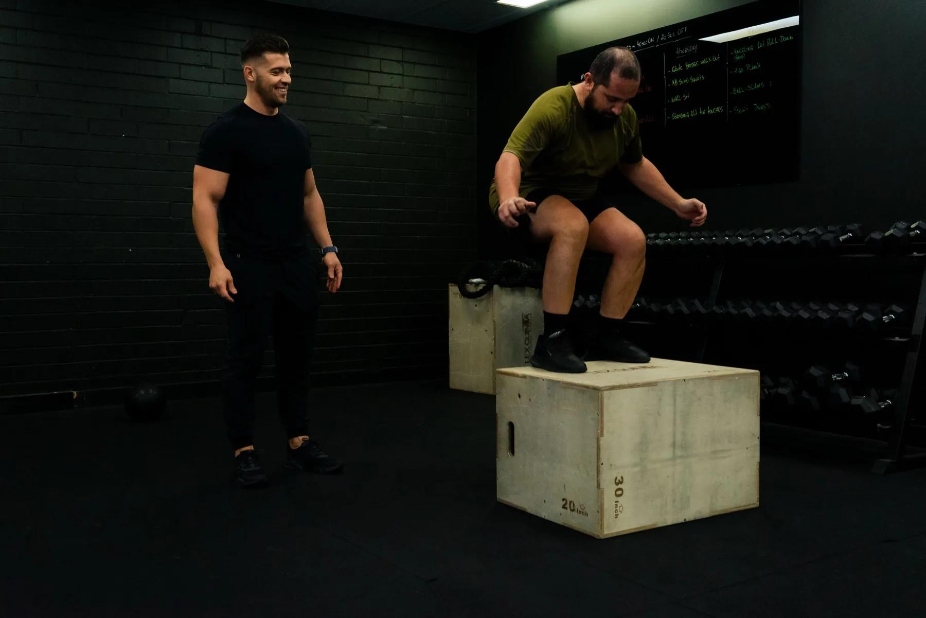 Client jumping onto a plyo box as Hudson supervises