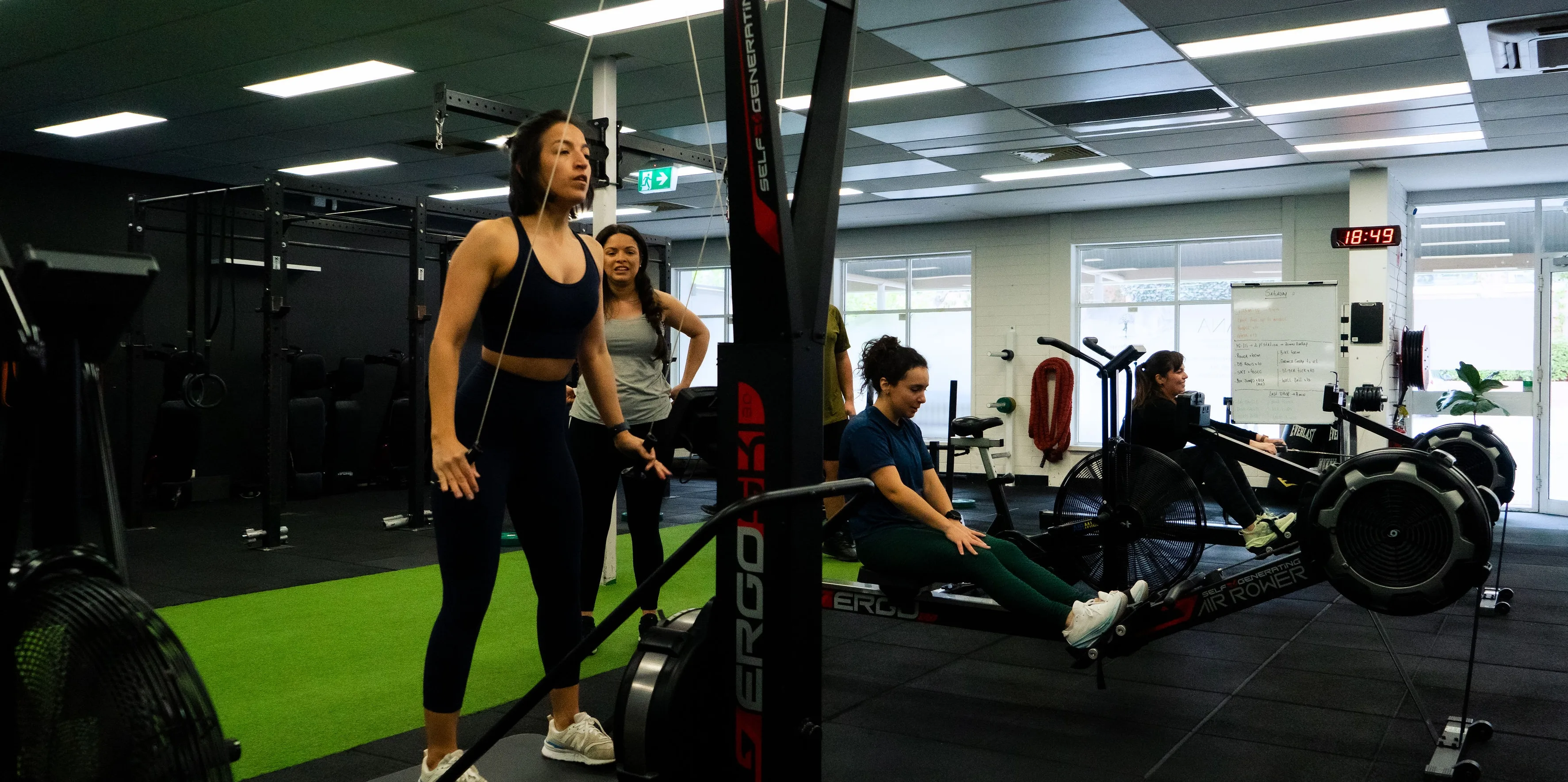 Hudson coaching clients through rowing and conditioning work in the gym