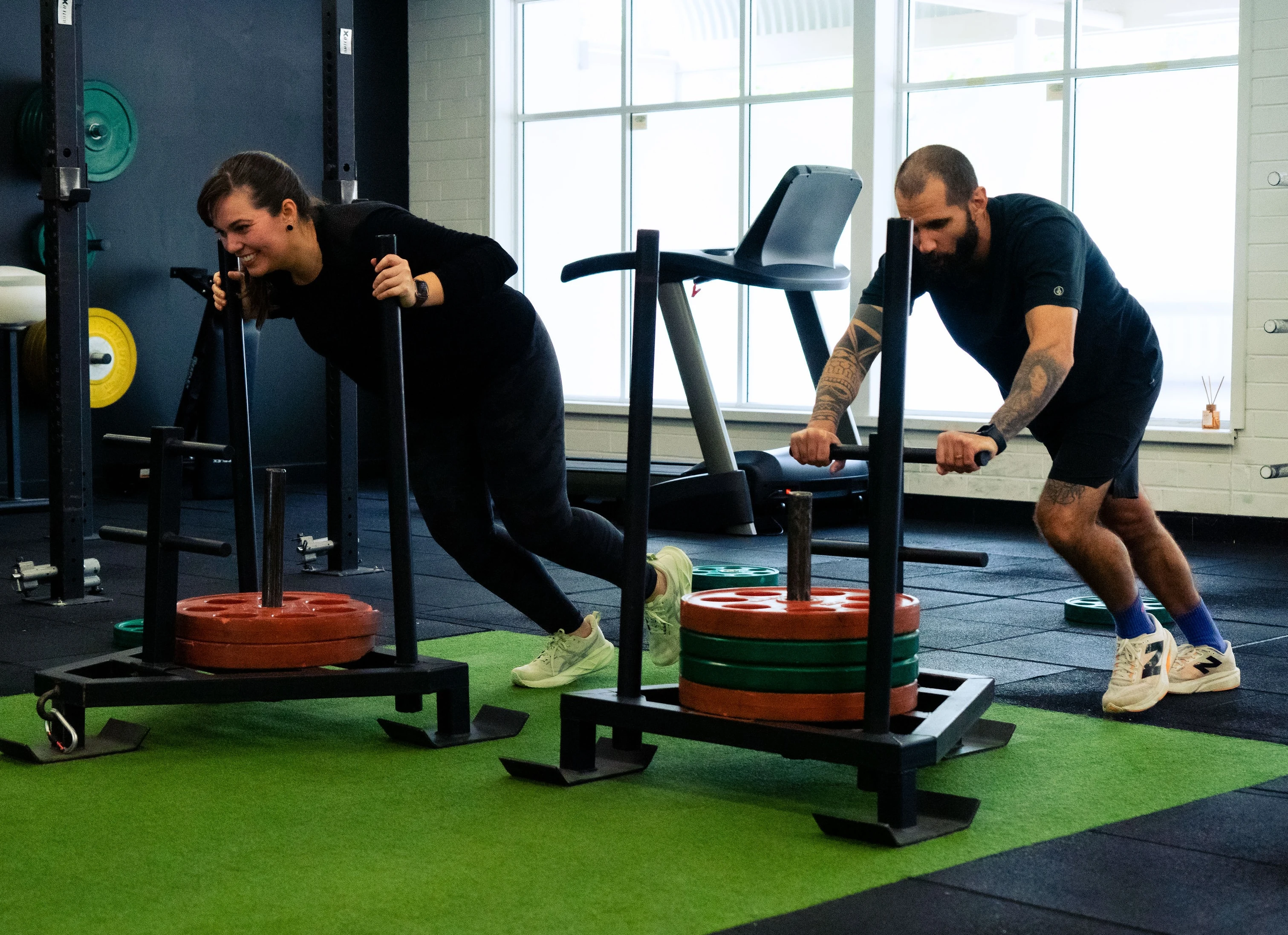 Hudson coaching clients through sled push strength training