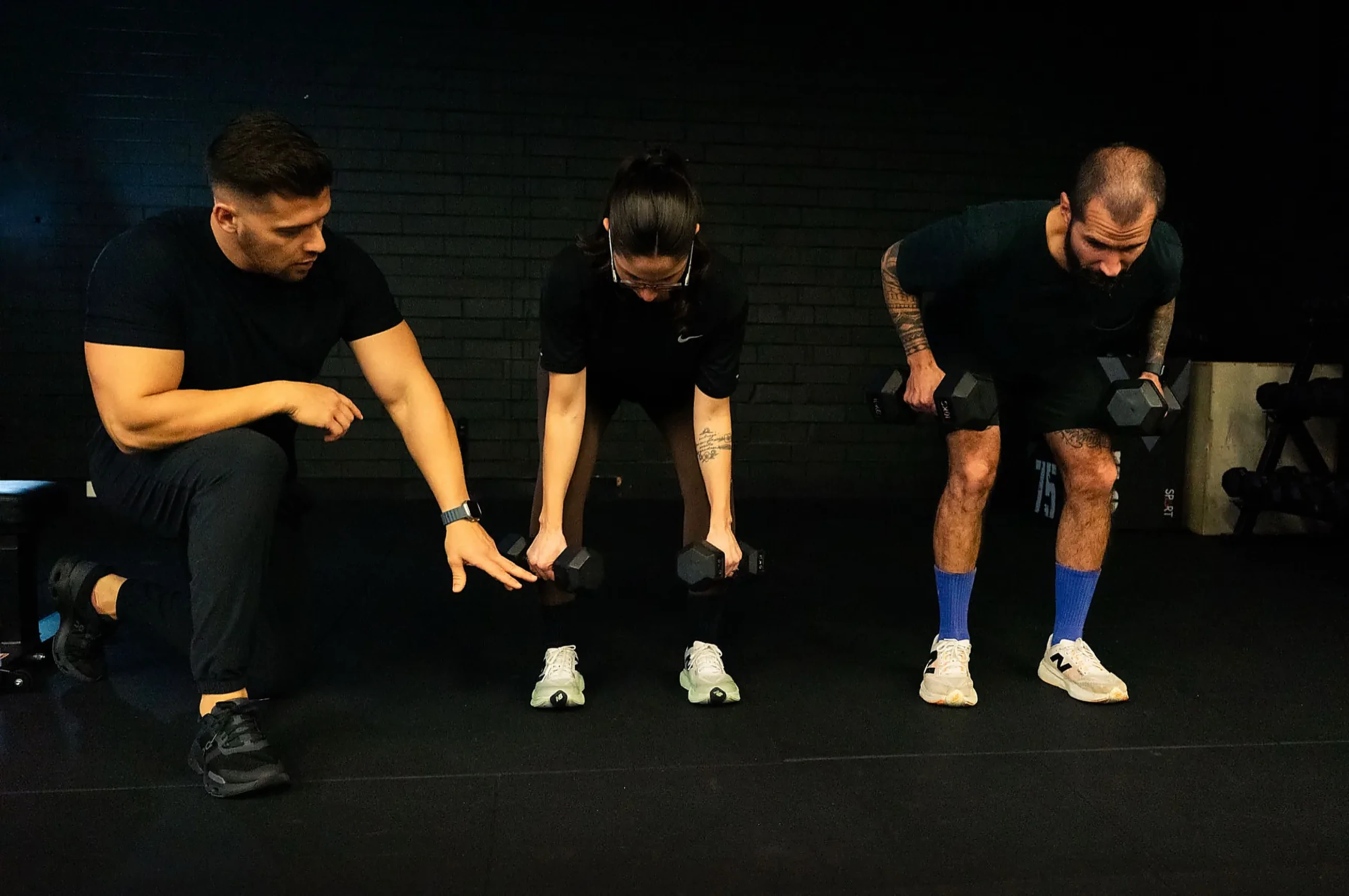 Hudson coaching two clients through dumbbell row technique