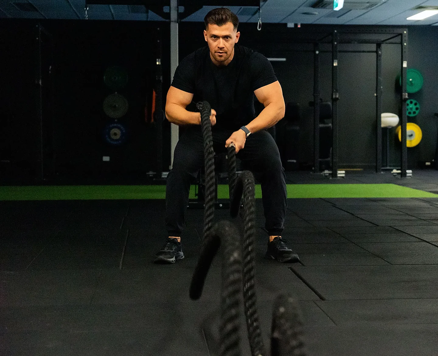 Hudson coaching a client through battle rope training